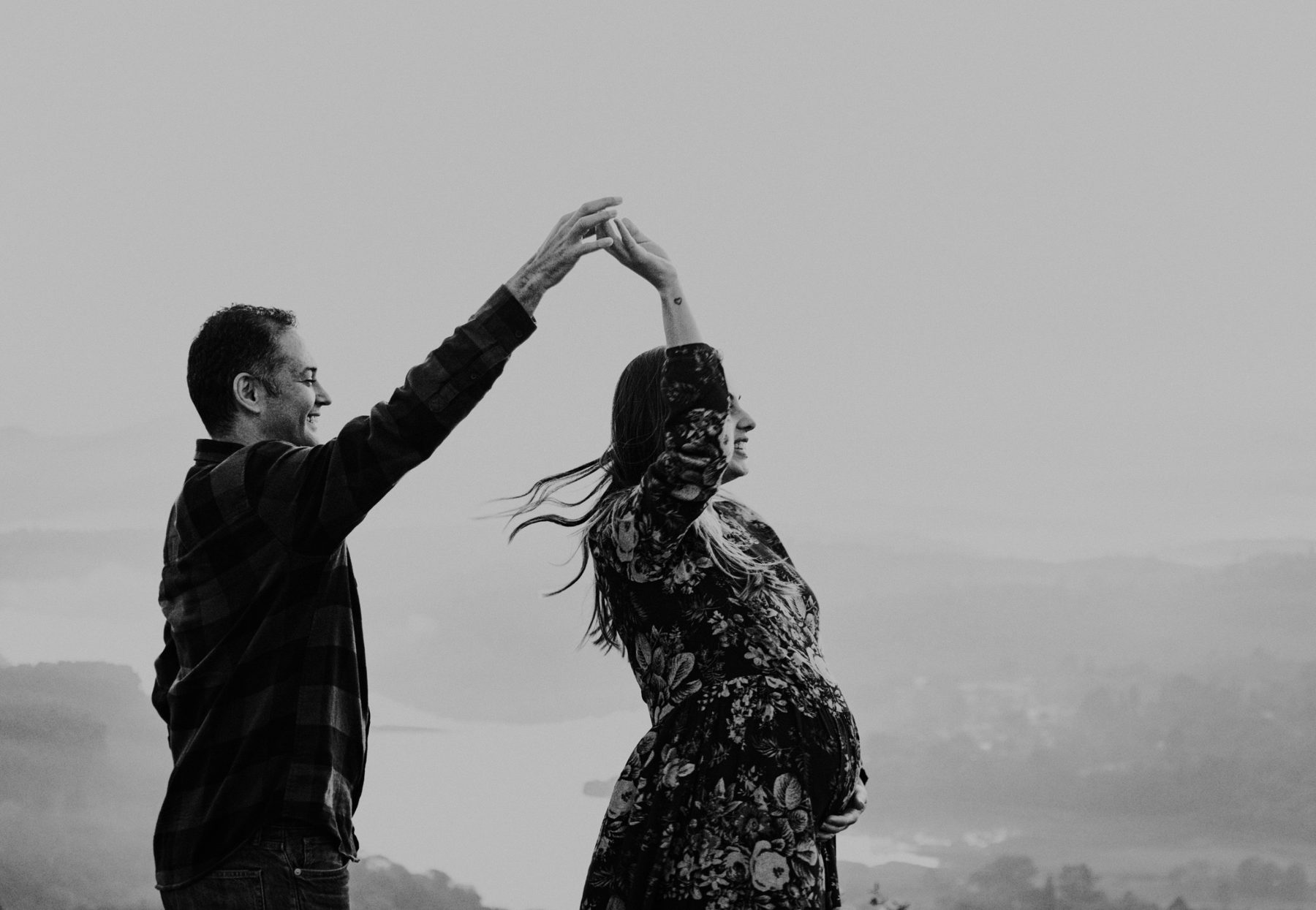 Casal dançando no alto de um morro com neblina, em preto e branco