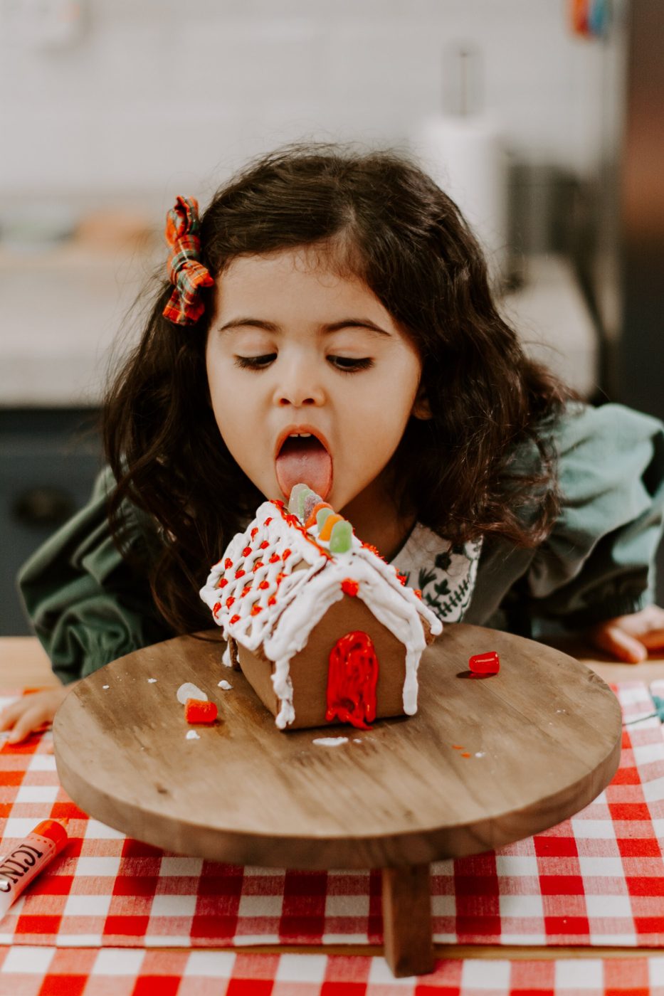 Menina lambendo o doce do telhado de uma casinha de biscoito