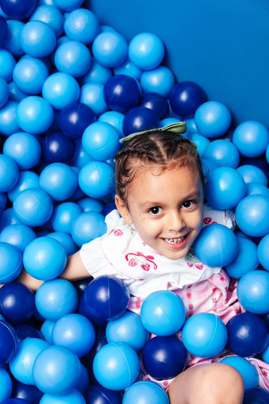 Menina sorrindo no meio de uma piscina de bolinhas azuis